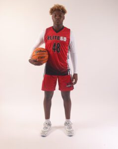 A boy in a red basketball jersey holding a ball (4)