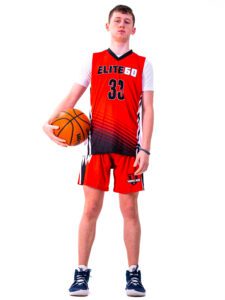 A boy in a red basketball jersey holding a ball on his side