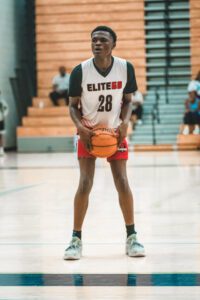 A boy in a white basketball jersey, shooting a ball