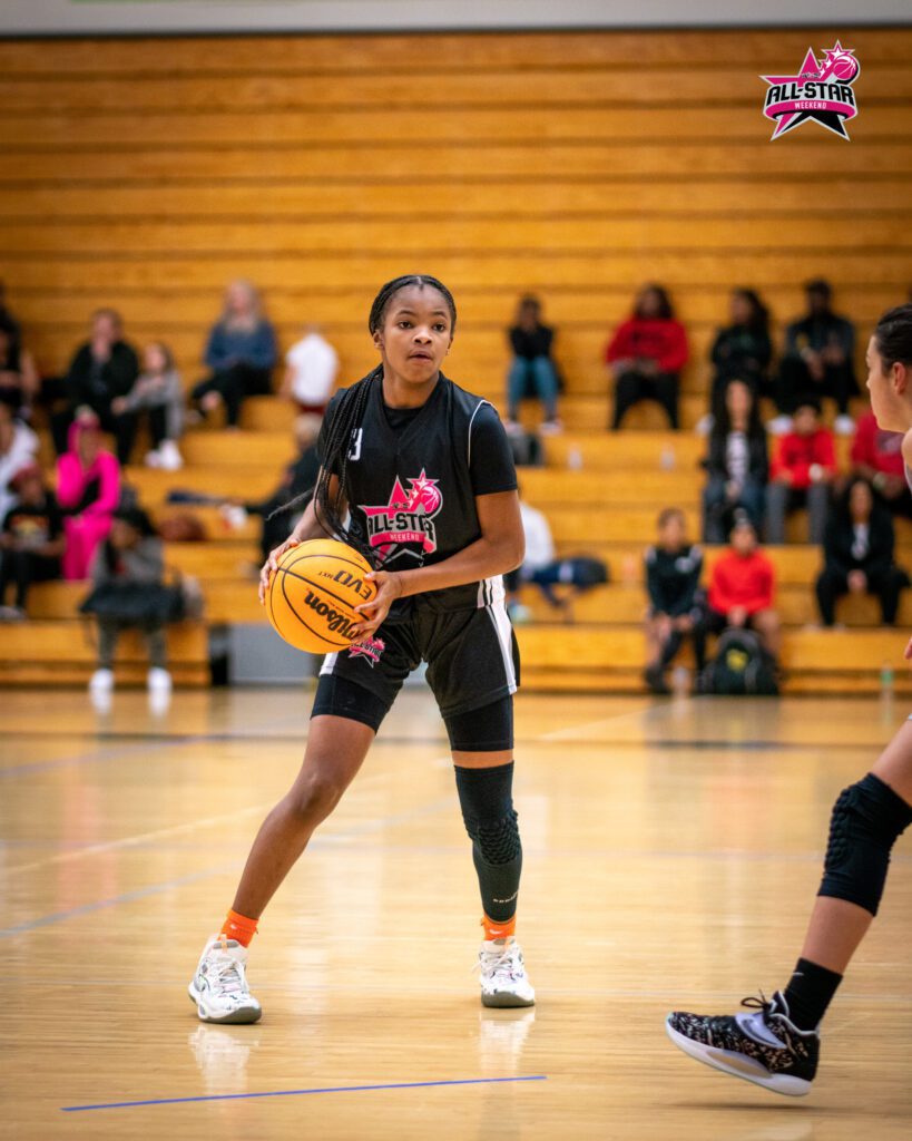 A girl in black jersey holding basket ball in her hand