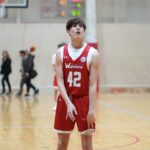 Young basketball player in red jersey preparing to pass or shoot.