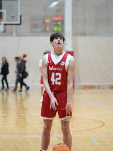 Young basketball player in red jersey preparing to pass or shoot.
