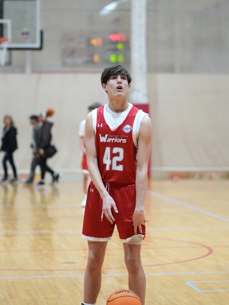 Young basketball player in red jersey preparing to pass or shoot.