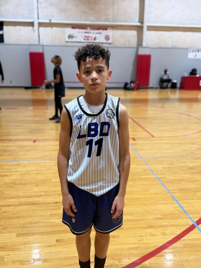 Young basketball player posing on indoor court in jersey number 11.