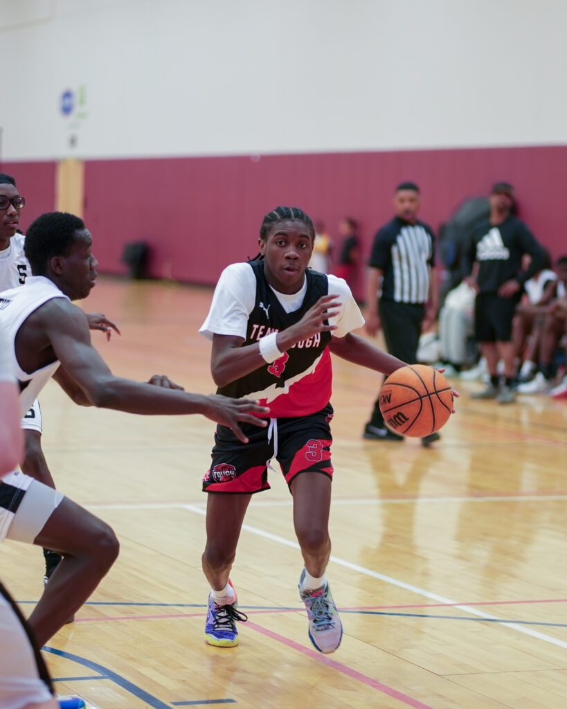Young basketball player dribbling past a defender during a game.