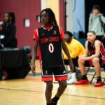 Young basketball player in uniform dribbling on court.