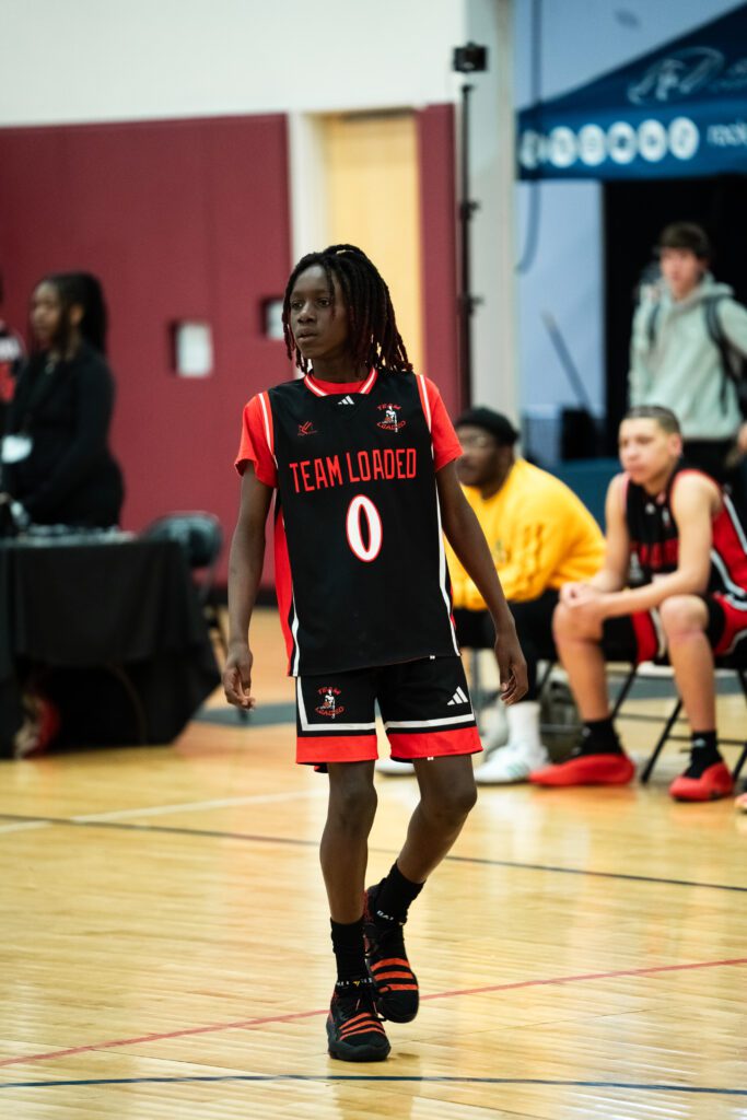 Young basketball player in uniform dribbling on court.