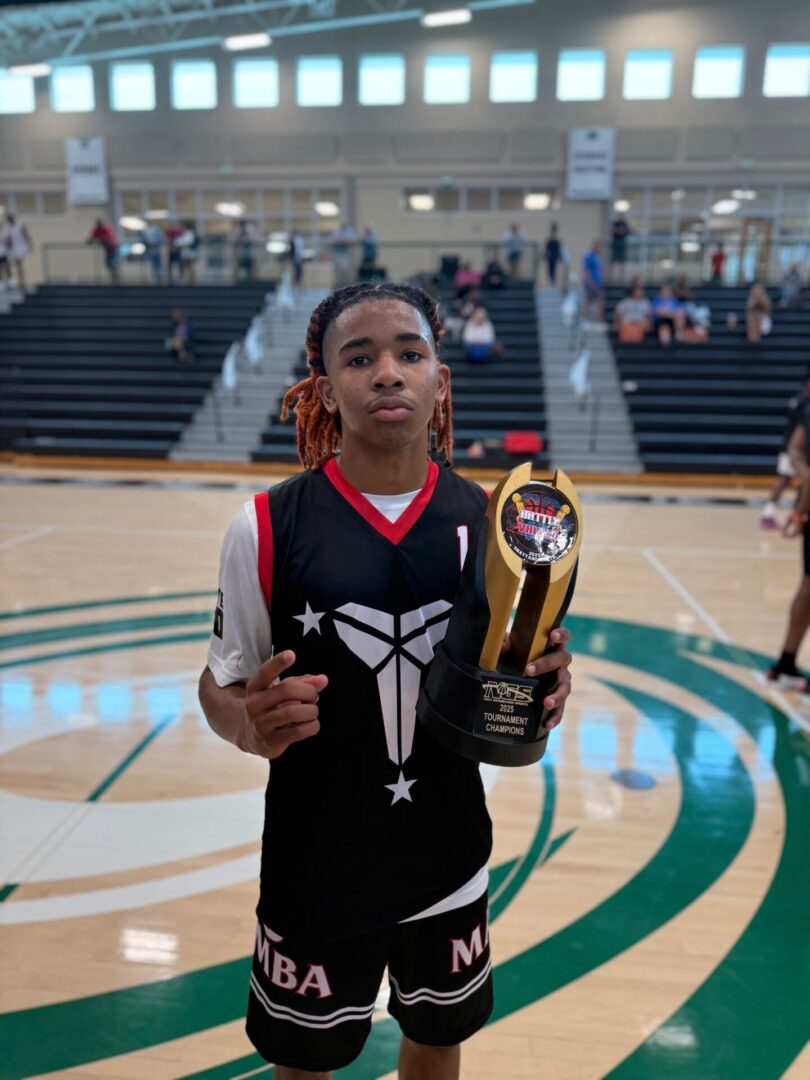 Young basketball player holding a trophy on the court.