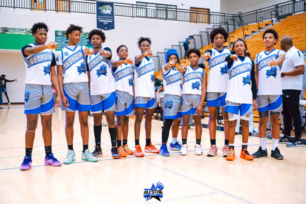 Young basketball team posing in uniforms on an indoor court.