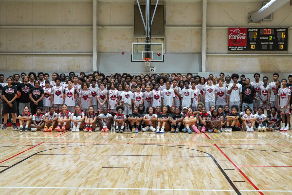 Large group of basketball players posing in a gym.