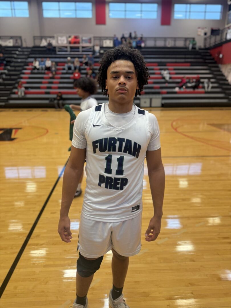 High school basketball player in white uniform posing on gym court.