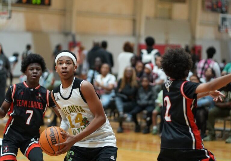 Youth basketball player in white jersey prepares to shoot.