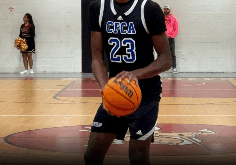 Joshua Sanders holding a basketball on an indoor court.
