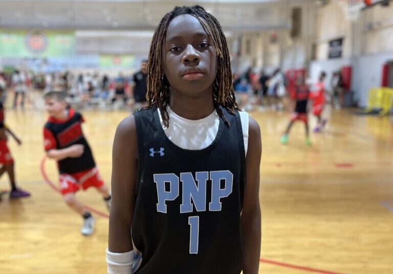 Young basketball player in black PNP jersey standing on court.