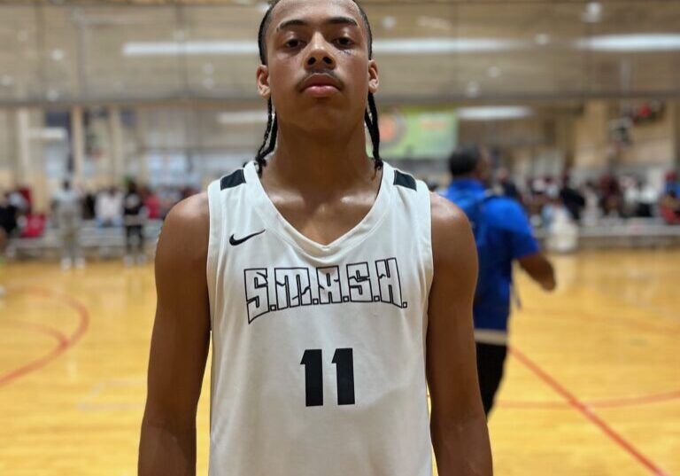 Young basketball player in white jersey standing on indoor court.