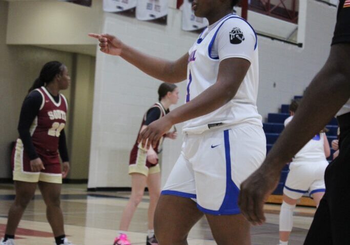 Female basketball player in white uniform pointing during a game.