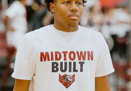 Young basketball player wearing a Midtown Built t-shirt on court.
