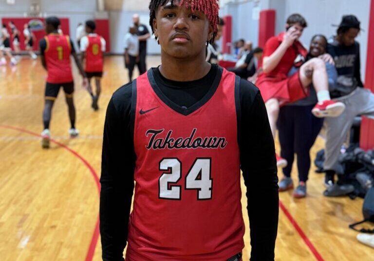 Young basketball player in red uniform posing on indoor court.
