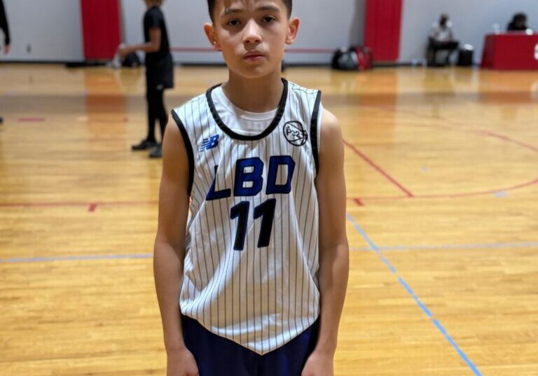 Young basketball player posing on indoor court in jersey number 11.