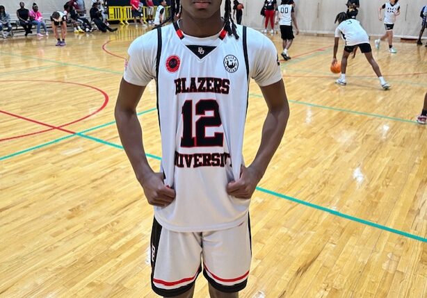 Young basketball player posing on indoor court in uniform.