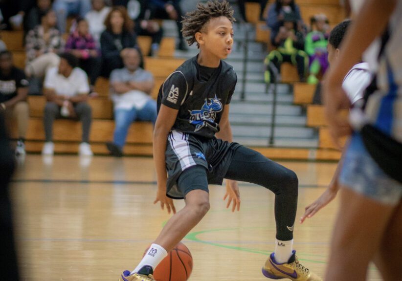 A boy in black jersey playing basket ball