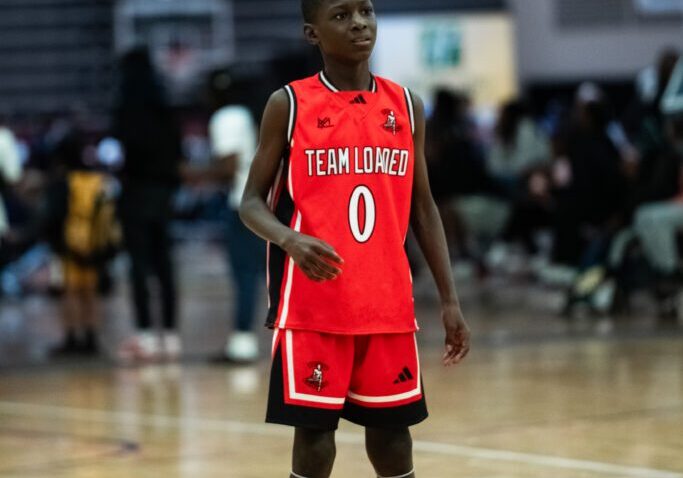 Young basketball player in red uniform standing on court.