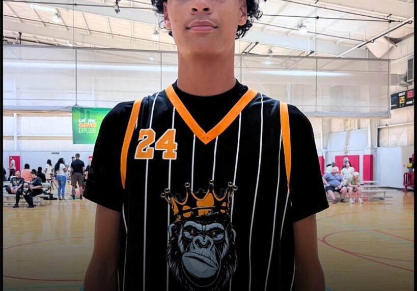 Young basketball player in striped jersey posing in gymnasium.