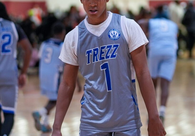 Young basketball player in gray and blue uniform on the court.