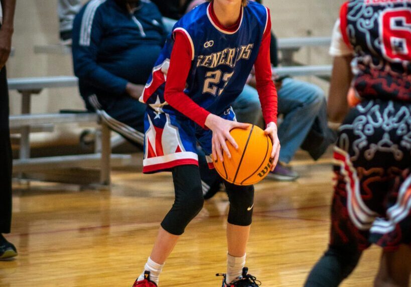 A girl in blue and red color jersey holding abasket ball