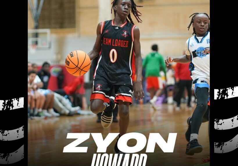 Young basketball player in black uniform holding a basketball indoors.