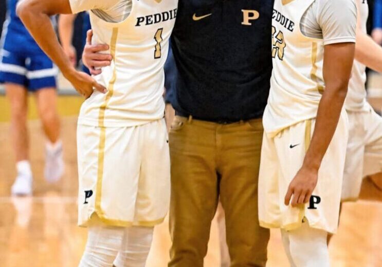 Basketball coach gives instructions to two players during a game.