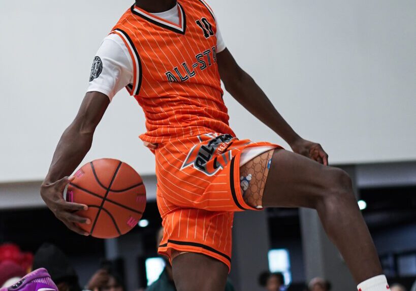 Basketball player in mid-air slam dunk during a game.